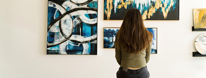 Woman sitting on bench looking at art on the wall